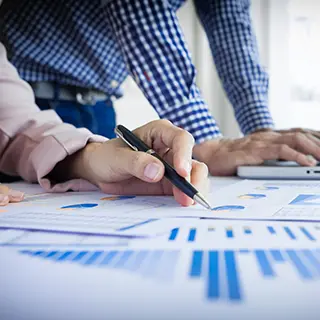 Deux personnes examinant des graphiques imprimés, stylo à la main