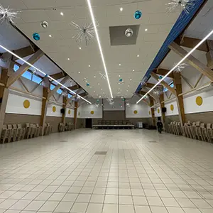 Intérieur d'une grande salle communale, chaises alignées le long des murs