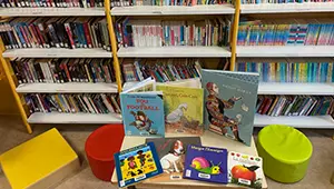 Albums jeunesse présentés sur une table basse, entre des poufs colorés et des rayonnages de livres