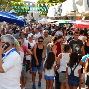 Visiteurs dans l'allée d'un marché provençal, sous des guirlandes de fanions