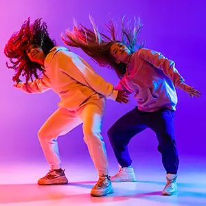 Deux jeunes danseuses de hip-hop en mouvement sur fond violet