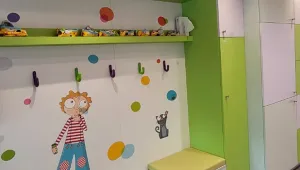 Vestiaire de la crèche aux murs blancs et verts décorés de pastilles colorées