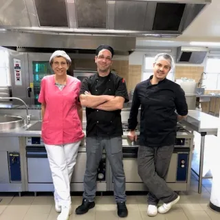 Trois membres de l'équipe de restauration debout devant les fourneaux de la cuisine