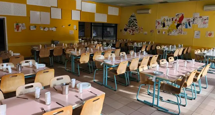 Réfectoire La Rocantine : tables dressées, chaises en bois et dessins d'enfants sur des murs jaunes
