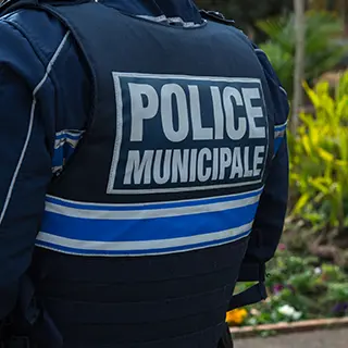 Policier municipal vu de dos, gilet marqué Police municipale