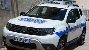Véhicule sérigraphié de la police municipale stationné devant un mur de pierre