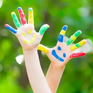 Mains d'enfants levées, peintes de couleurs vives et de visages souriants