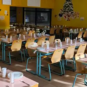 Réfectoire scolaire aux murs jaunes, tables dressées avant le repas