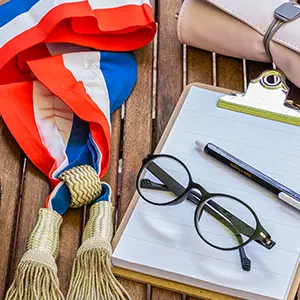 Écharpe tricolore, lunettes et bloc-notes posés sur une table en bois