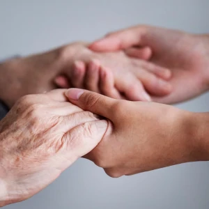 Mains d'une personne âgée tenues par celles d'une personne plus jeune