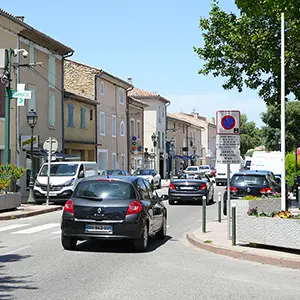 Rue de village bordée de maisons, voitures en circulation