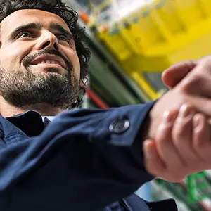 Homme souriant en veste de travail serrant la main de son interlocuteur
